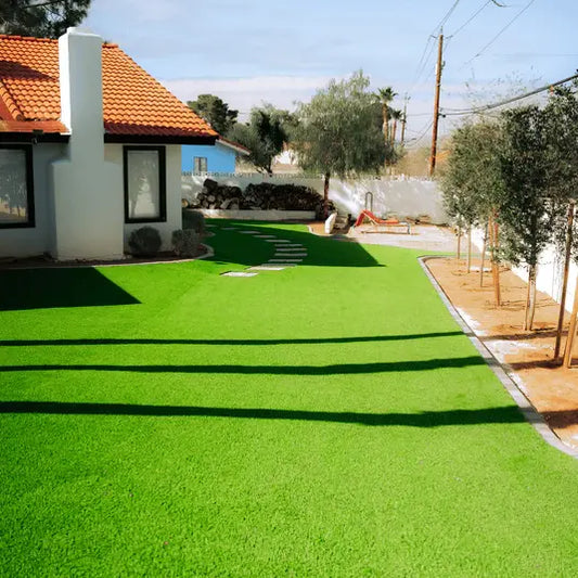 Artificial grass installation in a backyard with a house and trees in the background.