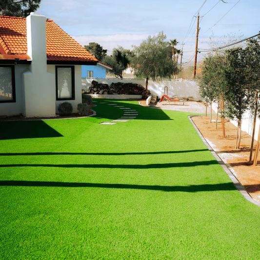 Artificial grass installation in a backyard with a house and trees in the background.