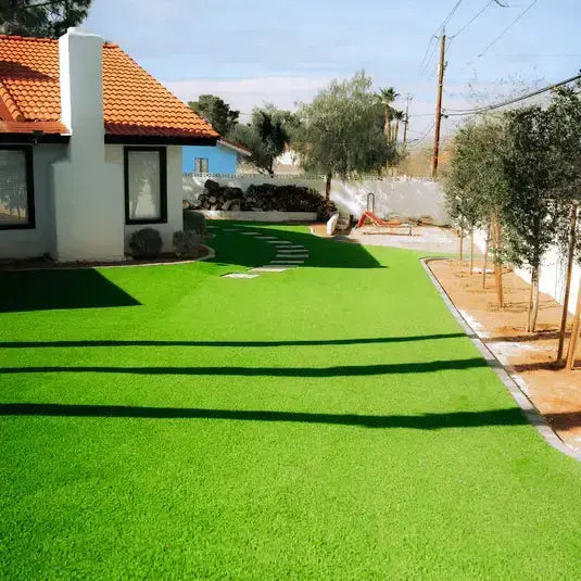 Artificial grass installation in a backyard with a house and trees in the background.