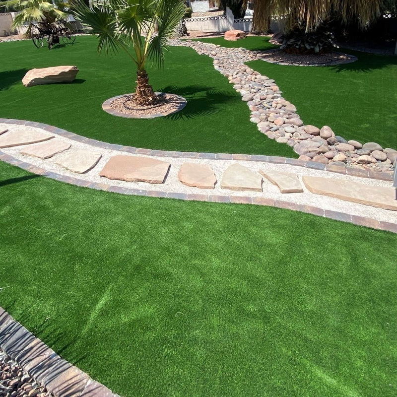 Palm-lined artificial-turf lawn with stone path and boulders